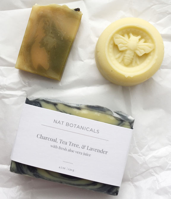Image of two homemade artisan soaps and a lotion bar with a bee impression.