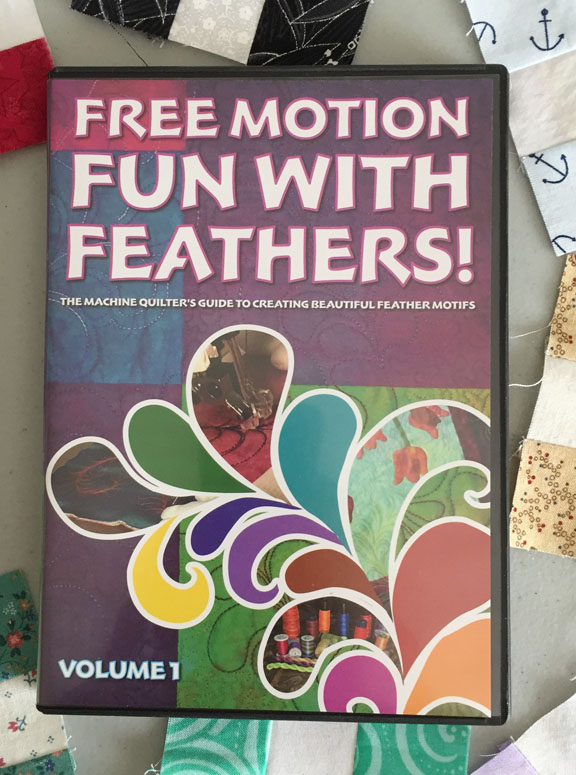 Image of the cover of a DVD called Free Motion Fun with Feathers! The Machine Quilter's Guide to Creating Beautiful Feather Motifs, Volume 1. The DVD rests on a background of small nine-patch quilt blocks.